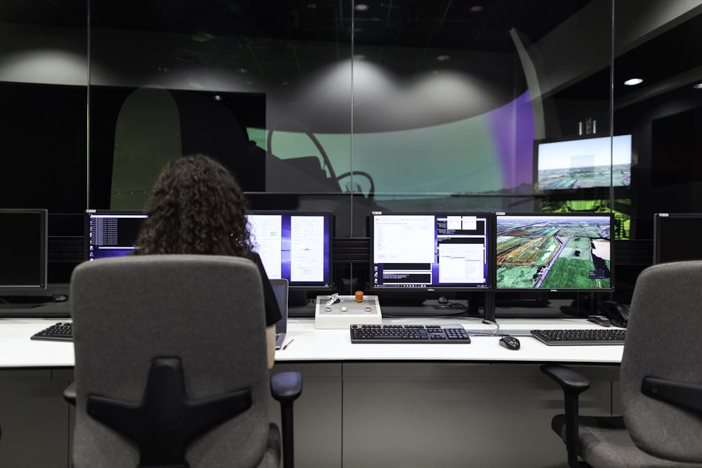 Female engineer managing multiple screens during a technology simulation in a control room.